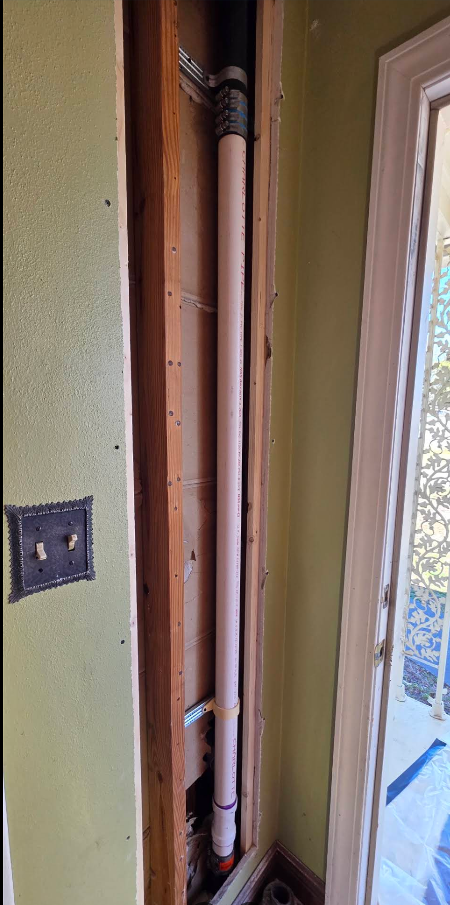 New PVC drain stack and insulated line installed inside an opened interior wall during a repipe