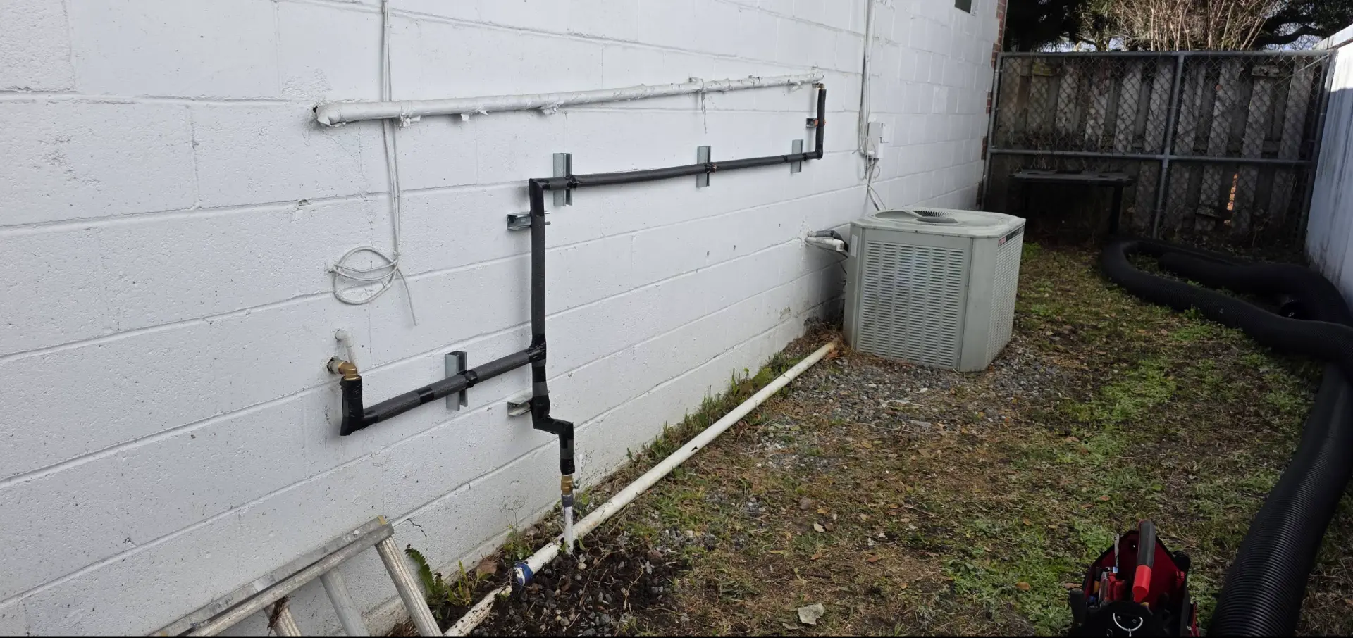 Insulated exterior water lines mounted on a commercial block wall with clean bracing and a new isolation valve