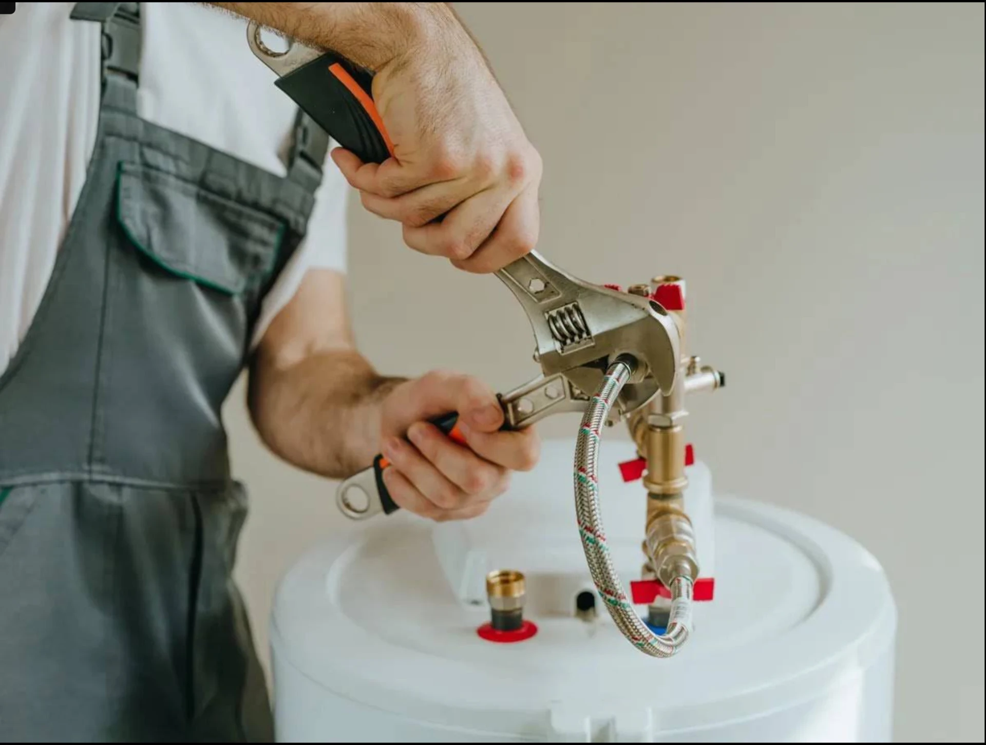 Plumber tightening the flexible supply connection on top of a new tank water heater during installation